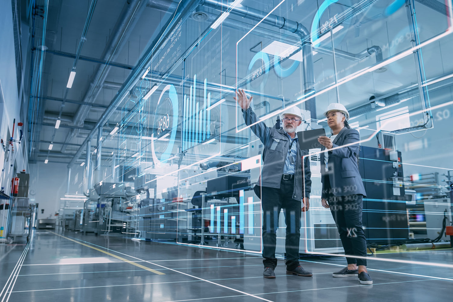 Ingenieure in moderner Produktionshalle analysieren digitale Daten zur Optimierung von Industrieprozessen mit Fördermitteln