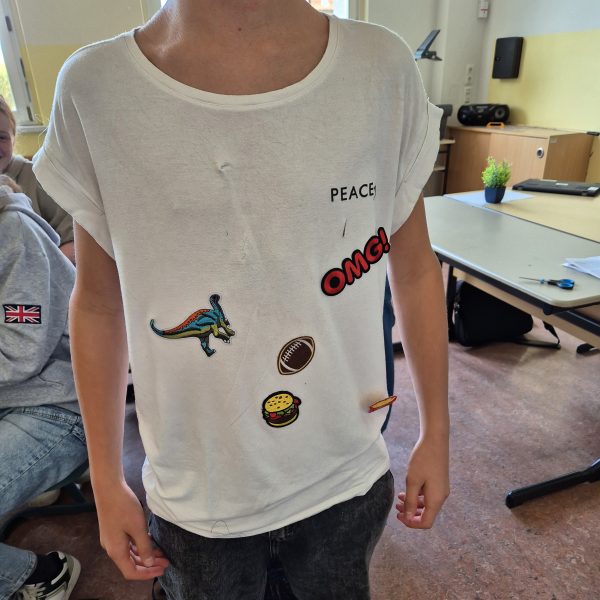Schülerprojekt im Klassenzimmer: T-Shirt mit aufgebügelten Motiven als kreatives Praxisbeispiel im Profilunterricht Nachhaltigkeit.