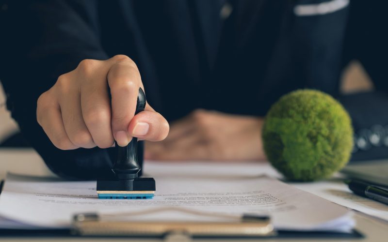 Hand setzt Stempel auf ein Dokument als Symbol für Zertifizierung und nachhaltige Unternehmensstandards bei Texulting